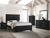 Black bedroom furniture set with bed, nightstands, and dresser in a room with white walls and wooden beams.